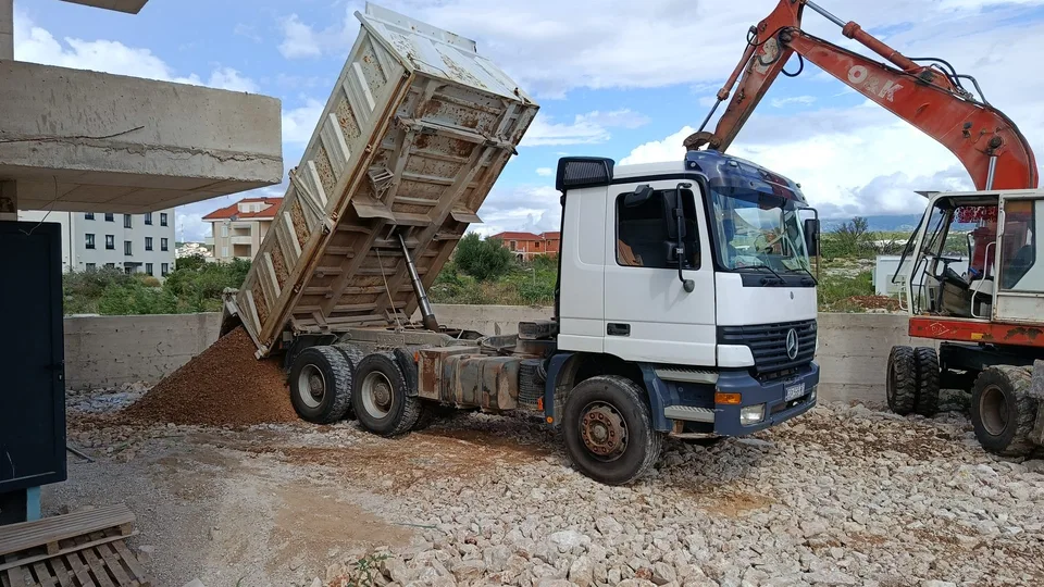 Kamion kiper istovaruje materijal na gradilištu — fotografija s terena