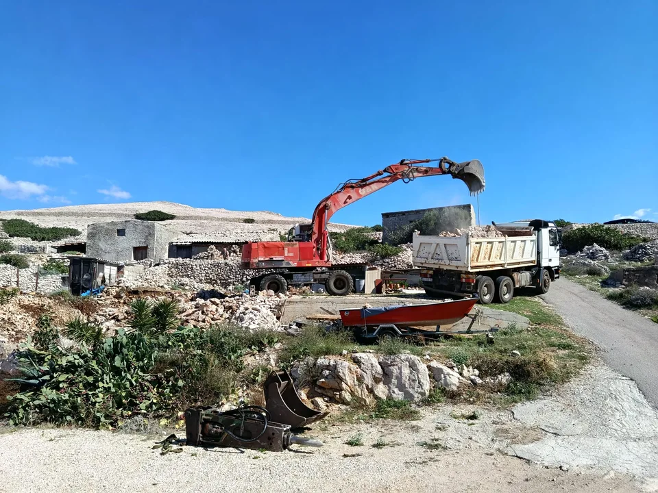 Bager utovaruje kamen u kamion, uz odloženi pikamer u prvom planu — fotografija s terena